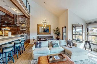 A living room with a large sectional sofa, a wooden coffee table, and a view of the mountains through the window.