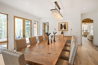 Dining area at Snow Chalet features a large wooden table surrounded by upholstered chairs.