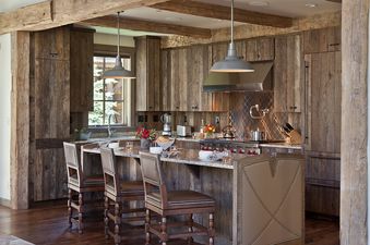 The kitchen at Fish Creek Lodge 02 features rustic wooden cabinetry, a large island with granite countertops, and modern stainless steel appliances, creating a blend of rustic charm and contemporary convenience.