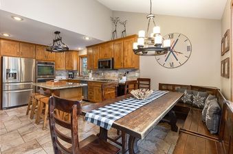The kitchen and dining area features wooden cabinetry, stainless steel appliances, and a large dining table with a checkered runner.