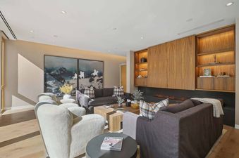 A modern living room in Founders Place 2303 with a fireplace, stylish seating, and abstract art.