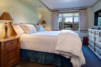 A peaceful bedroom at the Ranch at Steamboat RA201 featuring a cozy bed, wooden furniture, and a window with an outdoor view.