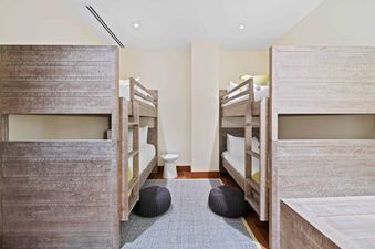 A bunk bed room with two sets of bunk beds, each with a white mattress and wooden frame.