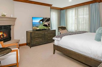 A large bedroom in Ritz Carlton Vail 402 with a fireplace, a king-sized bed, and large windows.
