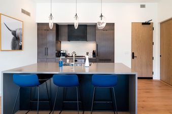 Modern kitchen with a sleek island countertop and three bar stools.