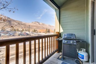 A private balcony at Powder Pointe 303B features a gas grill and offers views of snow-dusted mountains, a parking lot, and a clear blue sky.