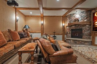 A luxurious home theater with comfortable couches and a large fireplace, perfect for relaxation and entertainment.