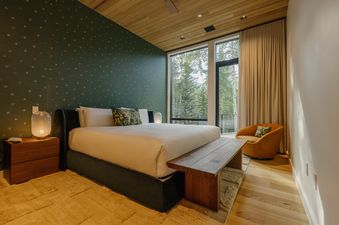 A luxurious bedroom at Vail Aspen Haven with a king-sized bed, stunning mountain views through large windows, and sophisticated design elements.
