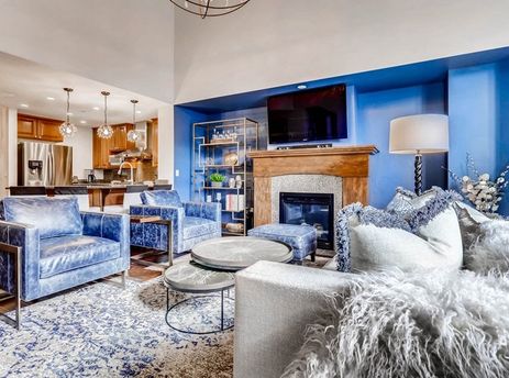 A living room with a fireplace, blue walls, and a large couch.