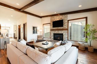 Living area at Mayflower Vista with a stone fireplace, cream sectional sofa, and dark wood accents.