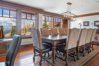 Dining area at Equinox at Empire Pass with a dining table and chairs, and windows looking out to the beautiful landscape.