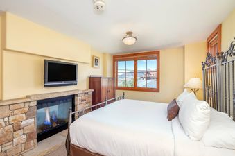 The bedroom in Lost Creek Two Bedroom Condo has a king-size bed, a fireplace, and a window with a view of the mountains.