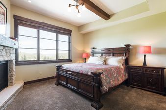 A spacious master bedroom at Silver Star 1303 featuring a large bed, fireplace, and a window with mountain views.
