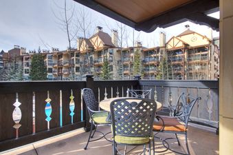Private balcony of the Arrabelle King Suite with a dining table and chairs overlooking the resort buildings.