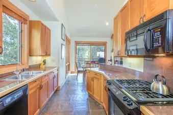 Fully equipped kitchen at Lynx at the Terraces with wooden cabinets and stone floor.