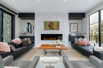 Modern living room at La Foret on Forest Road with a marble fireplace, black leather sofas, and a wooden coffee table.