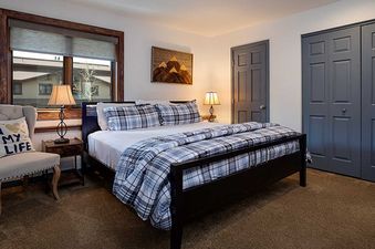 A king bedroom at Ranch at Steamboat RA215 with a king bed, nightstands, lamps, armchair, and mountain-themed artwork.