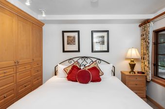 A cozy bedroom with a large bed, wooden furniture, and a window.