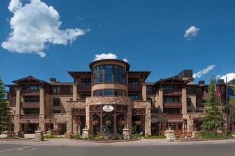 The Chateaux Deluxe Studio stands majestically under a bright blue sky, showcasing its stunning architecture with stone and wood accents.