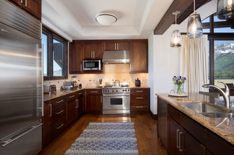 The Lumiere Five Bedroom Penthouse kitchen features stainless steel appliances, granite countertops, and custom cabinetry, with a view of the mountains.