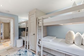 A cozy bedroom with wooden bunk beds, light blue walls, and integrated storage at Timberwind at Village Center.