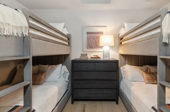 A close-up view of the bedroom featuring bunk beds, a dark dresser, and decorative art.