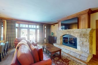 The spacious living room at Top of the World at Bachelors Gulch features a cozy fireplace and a large sectional sofa, perfect for relaxing after a day on the slopes.