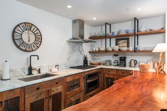 A modern kitchen with marble countertops, stainless steel appliances, and dark wooden cabinetry.