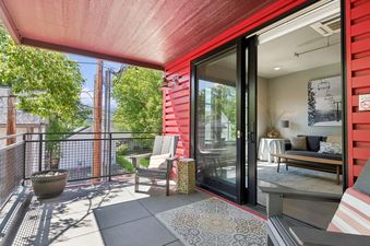 A private balcony with a red exterior and a view of green trees and mountains.