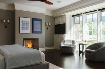 A cozy bedroom sitting area at Smoky Hollow with a fireplace and two modern armchairs near a large window.