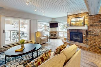 The living area features a warm fireplace and multiple windows looking out onto a snow-covered landscape.