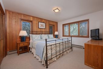 A cozy bedroom in Teewinot D4 with a metal-frame king bed and rustic wood-paneled walls.