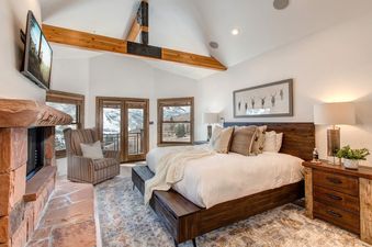 A bedroom with a king-sized bed, a fireplace, and a view of the mountains