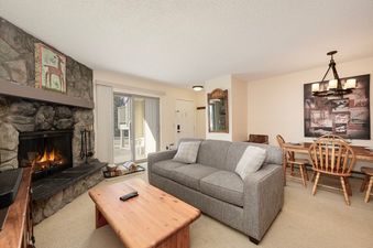 The living area within Meadow Ridge 18 features a cozy fireplace, comfortable seating, and an adjacent dining area, creating a perfect space for relaxation and entertaining.