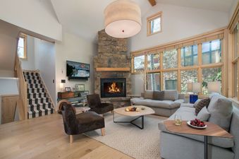A bright and cozy living room in Moose Creek 15 with a stone fireplace, comfortable seating, and large windows.