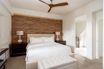 The bedroom at Moonlight Basin Saddle Ridge D1 has a king-size bed, two nightstands, a ceiling fan, a large window, and a wooden wall.