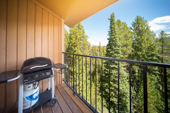 A close-up view of the gas grill situated on the spacious outdoor patio of Beaver Village 1134, surrounded by lush green trees and a clear blue sky.