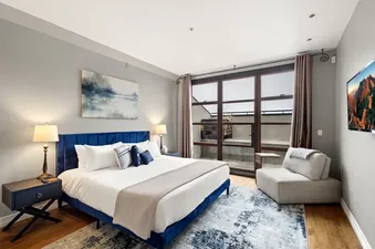 A luxurious bedroom with a blue velvet king-size bed, elegant bedside tables, and a large glass door leading to a balcony.