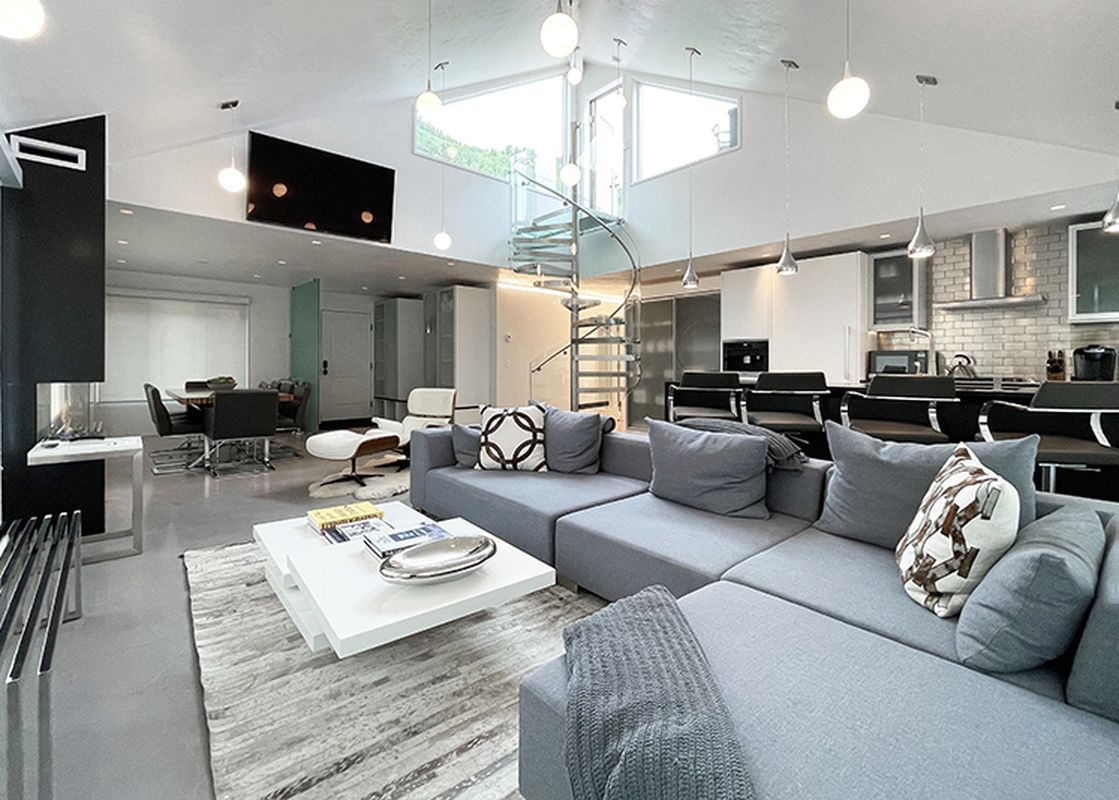 Modern living room with a grey sectional sofa, white coffee table, and a large flat-screen TV.