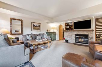 A living room with a fireplace, a sofa, and two armchairs.