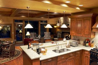 Fully equipped kitchen in Ski Vista Penthouse looking out towards the living and dining areas with a stone fireplace.