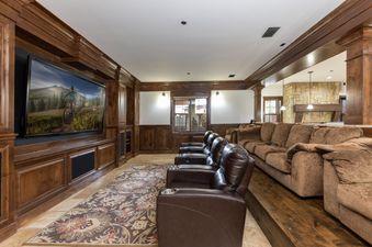 A luxurious home cinema at the Estate at Baldy Ridge features multiple rows of comfortable recliners and a large flat-screen television.