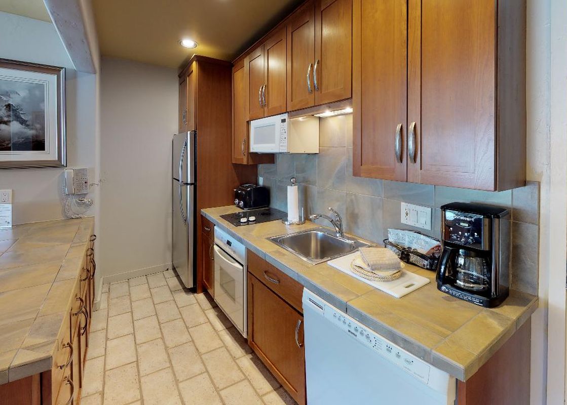 The kitchen in Manor Vail 166 Studio features a full-size refrigerator, oven, and dishwasher.