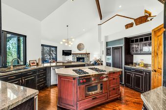 The kitchen in the Deer Valley Solamere Home has a large island with a cooktop and a sink near the window.