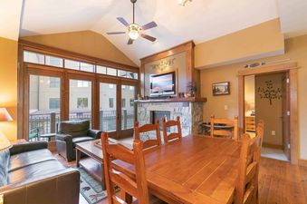A living room with a fireplace, leather couches, and a dining table with chairs.
