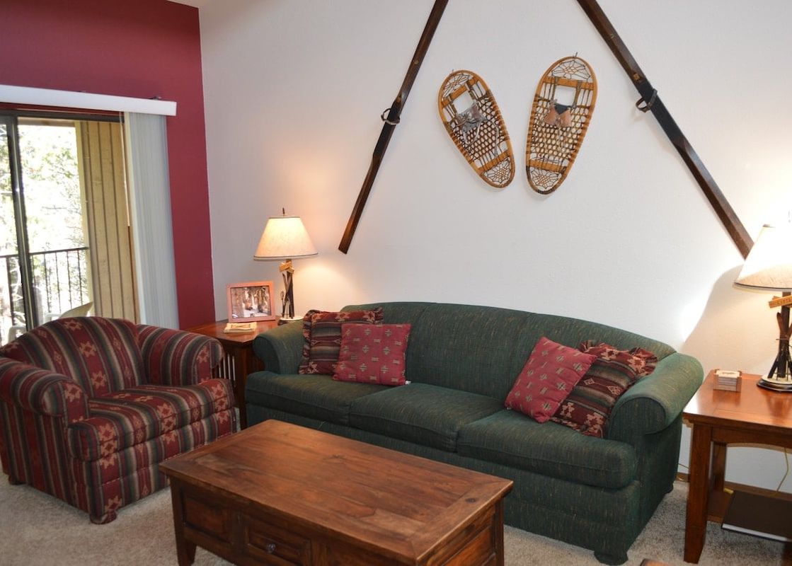 The living area at Beaver Village 1633 features a green sofa and a patterned armchair, complemented by a wooden coffee table and end tables with lamps.