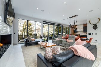 A luxurious and spacious open-concept living room at La Foret on Forest Road featuring floor-to-ceiling windows with a snowy mountain view.