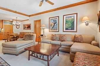The living and dining areas of The Charter D2505 feature plush sofas, a rustic wooden coffee table, and an adjacent dining set with wooden chairs.