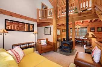 The open-plan living area of 980 Mulligan features a cozy fireplace, comfortable seating, and an adjacent dining space with an exterior view.