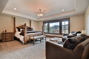 A luxurious bedroom in Powder Haus with a four-poster bed and mountain views from large windows.